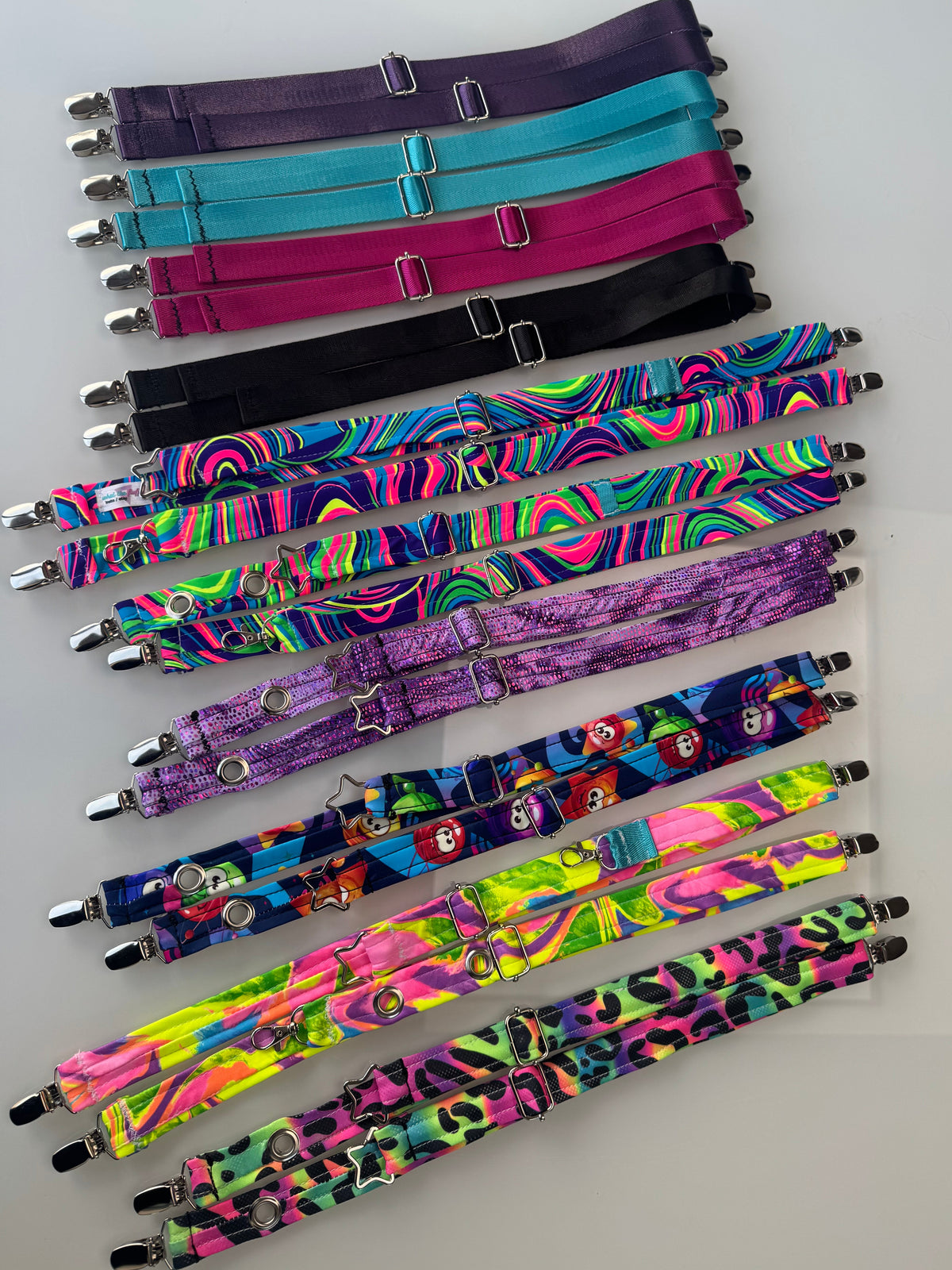 The Universal Magic Straps shown flat-laid in tons of different colors with silver attachment point hardware.